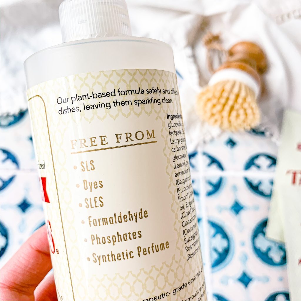 Lists of "free from" ingredients on the back of a bottle with scrubber brush and blue and white tile background