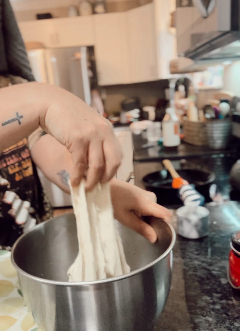 woman with tattoos performing the stretch and fold method with sourdough