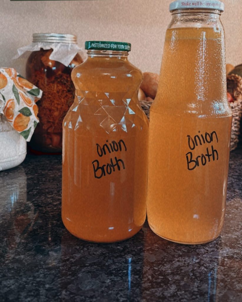 two bottles sitting on a counter labeled "onion broth" with sourdough starter and fire cider in the back ground.